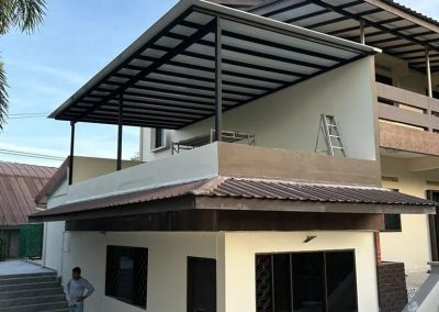 Wide view of aluminum roof awning installed on the second floor of a house, with a man standing on the ground floor