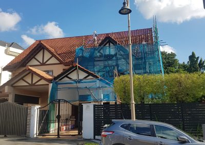 Roofing work in progress on the right side of a residential house, with a worker on top