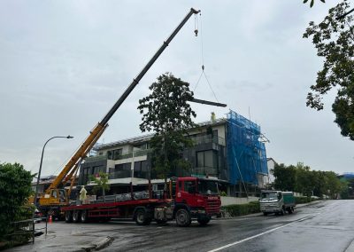 Crane lifting heavy metal roof materials from a red truck and placing them on a rooftop