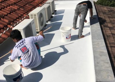 Two skilled workers applying waterproof coating to an RC roof