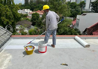 Employee applying sheet membrane waterproof coating on a roof, wide view with equipment