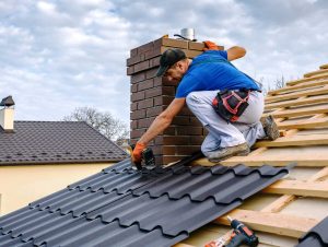 Man installing and fastening flashing on the roof beside a chimney