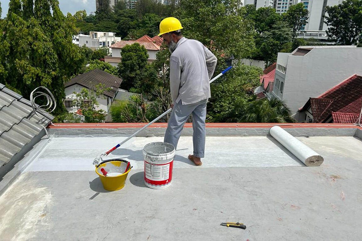 Employee applying sheet membrane waterproof coating on a roof with equipments