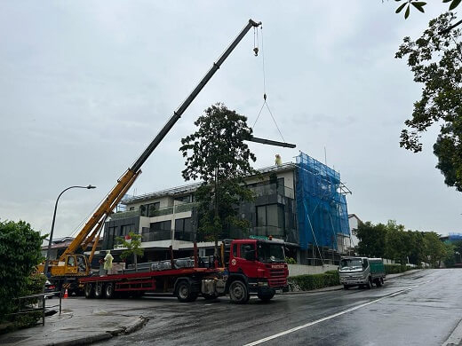 Crane lifting heavy metal roof materials from a red truck and placing them on a rooftop