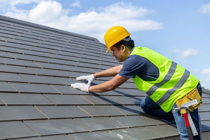 Man with pliers working on asphalt shingles on a roof