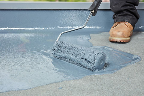 Employee applying sheet membrane waterproof coating on a roof with equipments